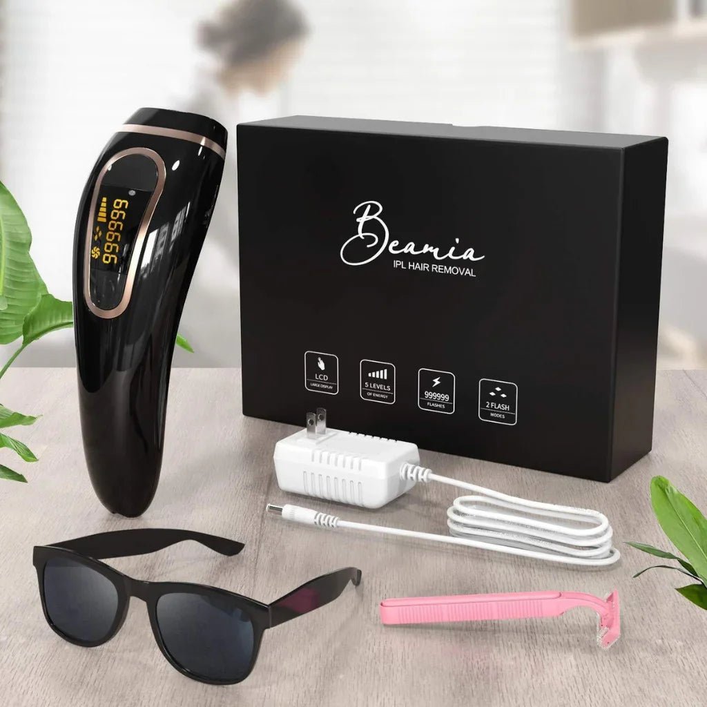 Beania IPL hair removal device with packaging, sunglasses, charger, and clip on a light surface.