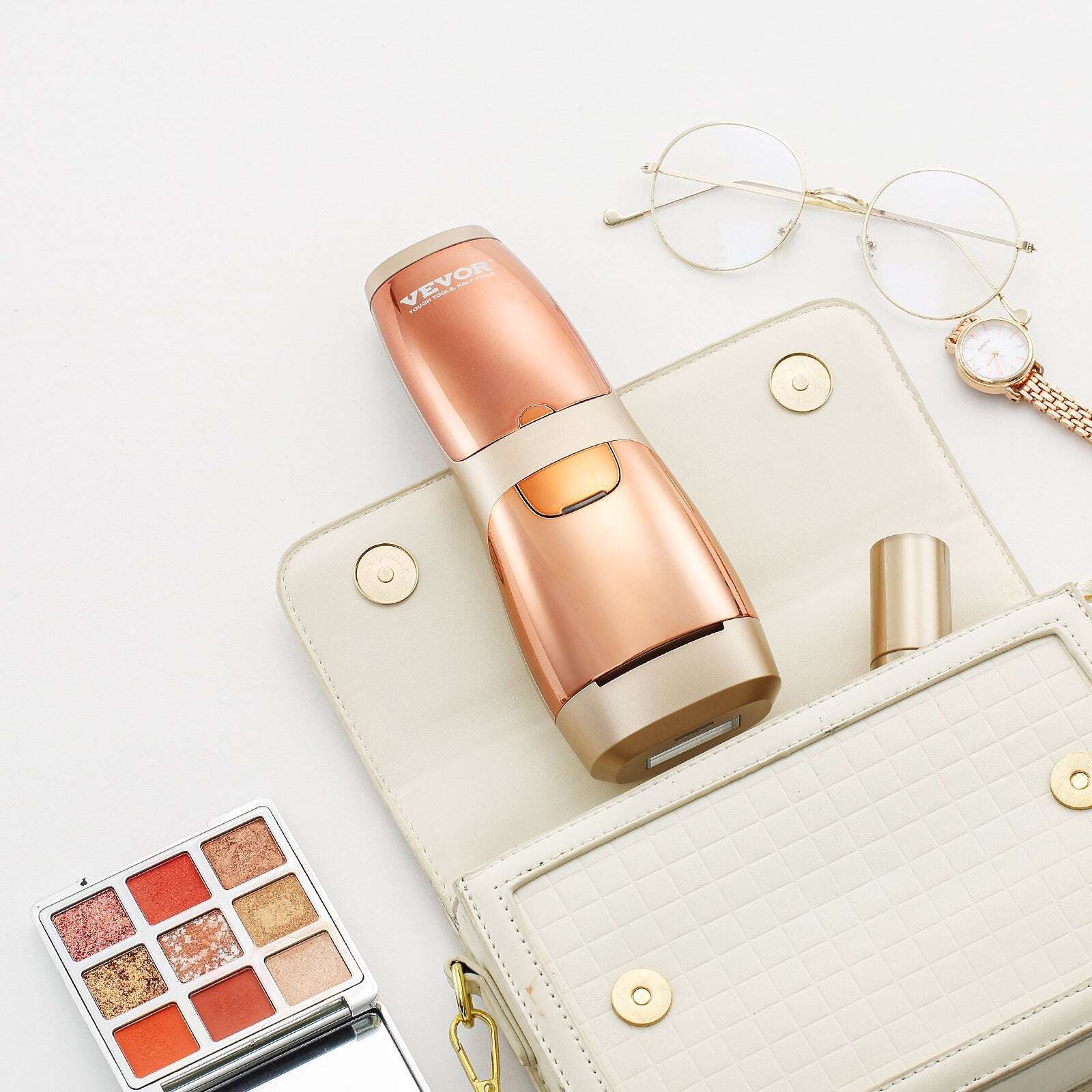 Rose gold VevoIPL hair reduction device on a white surface with a wallet, eyeglasses, and makeup palette.