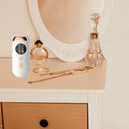 White IPL hair removal device on a vanity with perfume bottles and jewelry